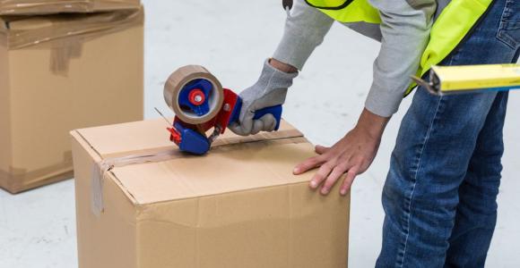 Stagiaire emballant un carton dans une formation logistique